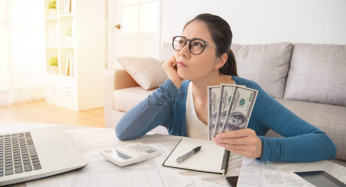 Attractive young mixed race asian woman working on finances worried about the expend cost sitting on sofa in the living room at home. interior and domestic housework concept.